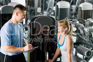 Personal trainer with young woman at gym