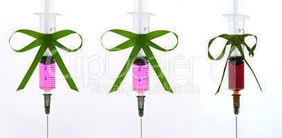syringes pink liquid with ribbons of grass
