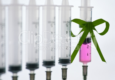 syringes pink liquid with ribbon of grass