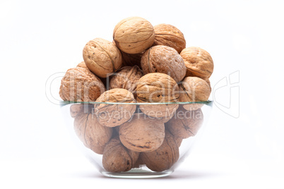 Walnuts lie in a glass bowl isolated on white