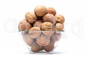 Walnuts lie in a glass bowl isolated on white