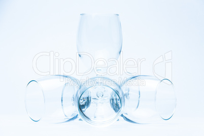 Wine glasses stand and lie symmetrically on white