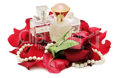 Perfume and pearl necklace in rose petals. Isolated.