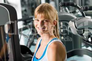 Smiling woman at fitness center exercise machine