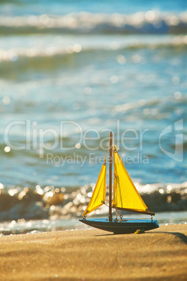 The little toy boat stands on sandy beach