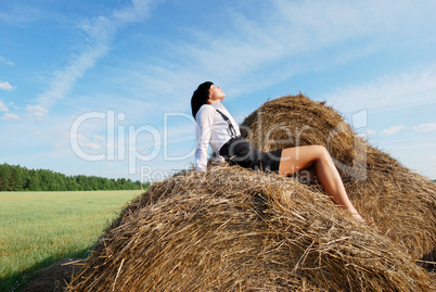 Woman on hay bale in summer field