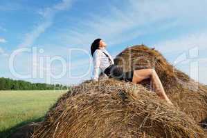 Woman on hay bale in summer field