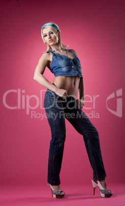 Cute sexy girl posing in jeans on pink background