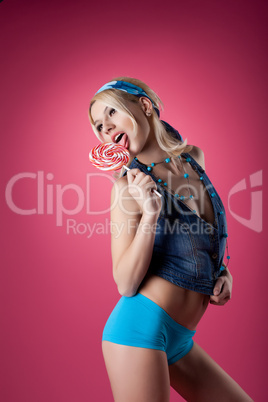 beauty blond girl lick candy on pink background