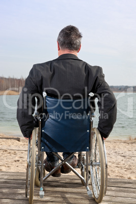 Mann sitzt im Rollstuhl in der Natur