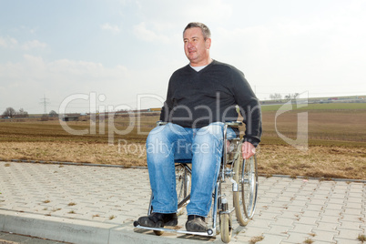 Man with a wheelchair on road pavement