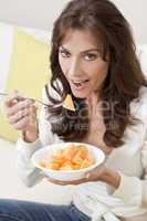 Brunette Woman Eating Melon At Home on Sofa