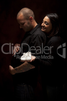 Mixed Race Couple Holding New White Baby Shoes on Black