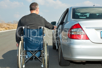Man in a wheelchair next to his car