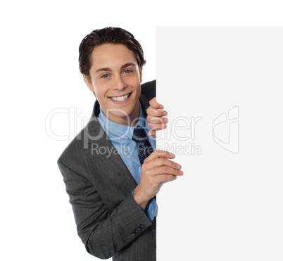 Businessman peeping from behind the blank board