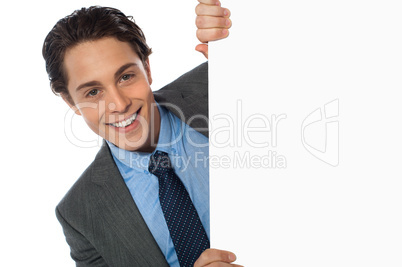 Businessman peeking behind a whiteboard