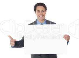 Male executive pointing towards blank billboard