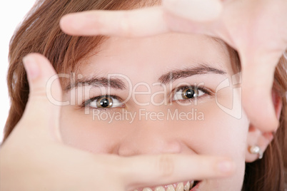 Pretty adult woman looking through a frame made by her hands.