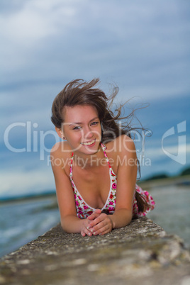 Beautiful girl in a light dress lying on a stone pier