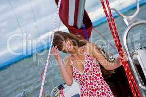 Beautiful girl in light dress standing on the deck of sailboat