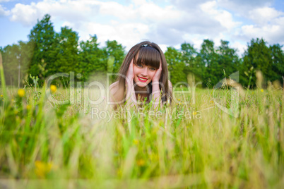 Pretty girl in red sarafan lies on the green grass