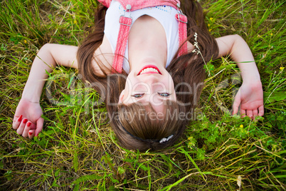 Pretty girl in red sarafan lies on the green grass