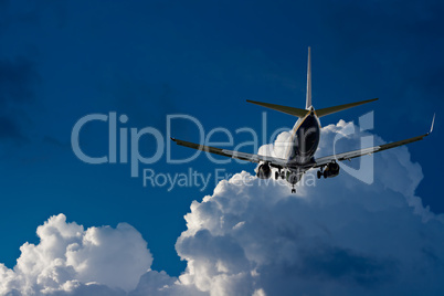 Passenger jet landing against a blue sky with white fluffy cloud