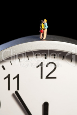 Miniatur Paar umarmt sich auf einer Uhr stehend