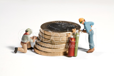 Miniatur arbeiter schweissen an einem Stapel Euro Münzen
