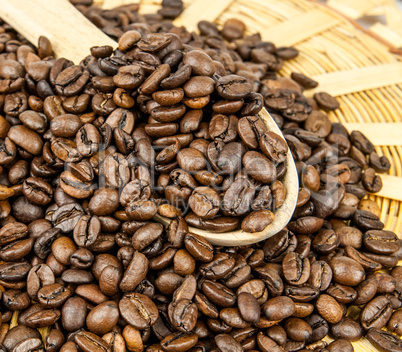 Coffee beans in a wooden spoon and as a background.