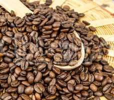 Coffee beans in a wooden spoon and as a background.