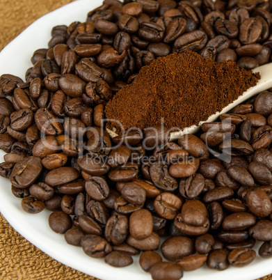 Coffee beans and ground coffee in a spoon.