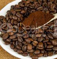 Coffee beans and ground coffee in a spoon.