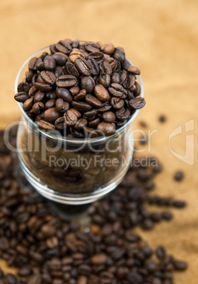 Grains of black roasted coffee in transparent cup