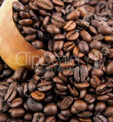Coffee beans in a wooden spoon and as a background.