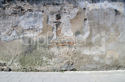 The broken wall near to sidewalk.