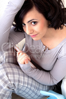 beautiful woman is sitting on the sofa an reading a book