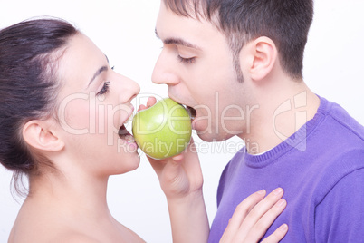 young couple with a green apple between their lips