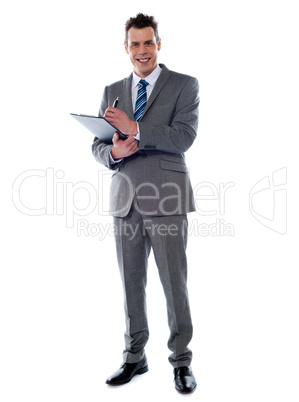Smiling businessman writing on clipboard
