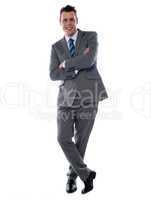 Cheerful young businessman leans against wall