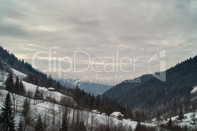 Mountain valley in winter under cloudy sky