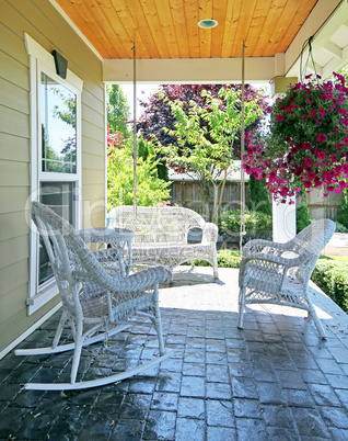 Front porch with white furniture and flowers.
