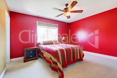 Red bedroom with bed and nighstand.