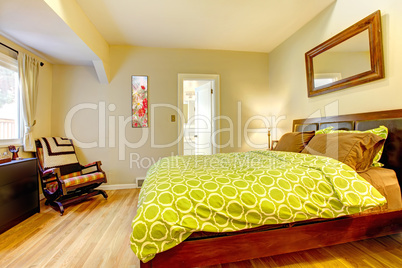 Modern green and beige bedroom with brown bed.