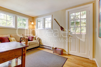 Room with sofa, door and desk in natural colors.