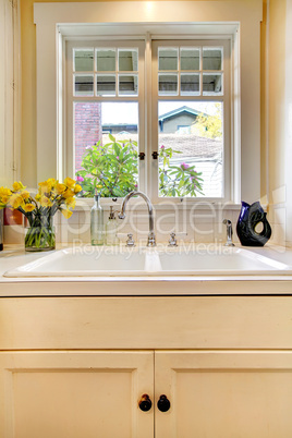 Kitchen sink and white cabinet with window.