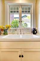 Kitchen sink and white cabinet with window.