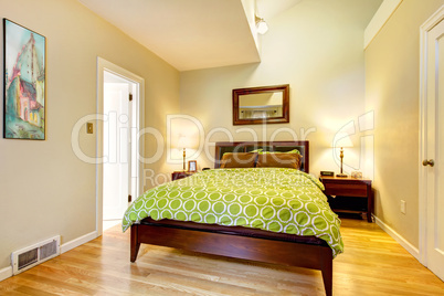 Modern green and beige bedroom with brown bed.