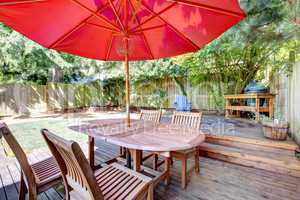 Back yard large deck with red umbrella and chairs.