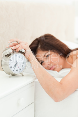 An alarm clock showing the time being silenced by a woman lying